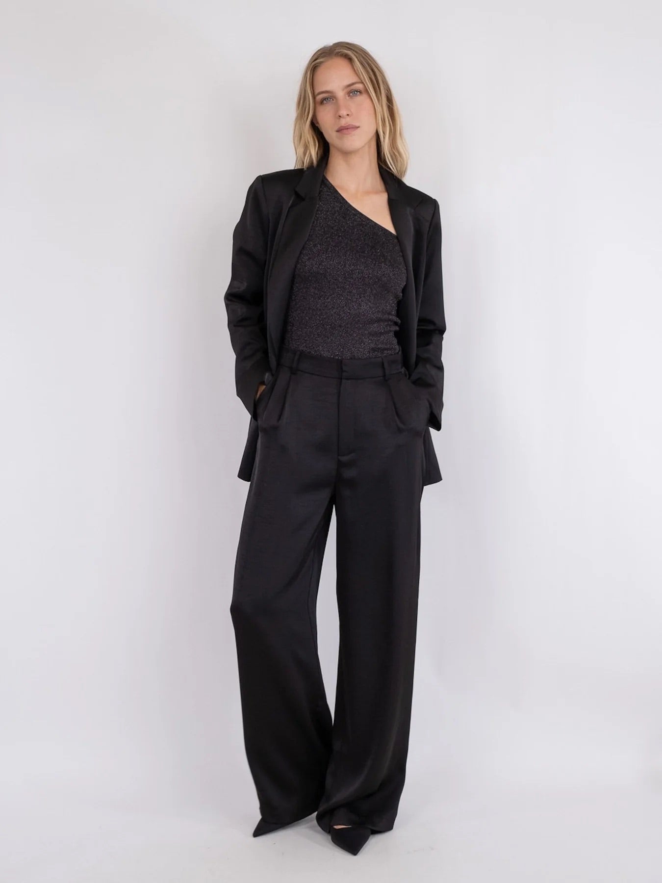 Model in een zwarte satijnen Neo Noir Alessandra broek met een blazer.