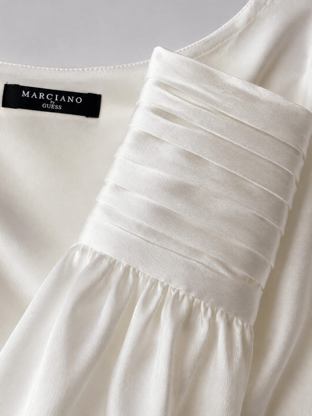 Detail van de stof van een crèmekleurige satijnen Marciano by Guess blouse met watervalhals.