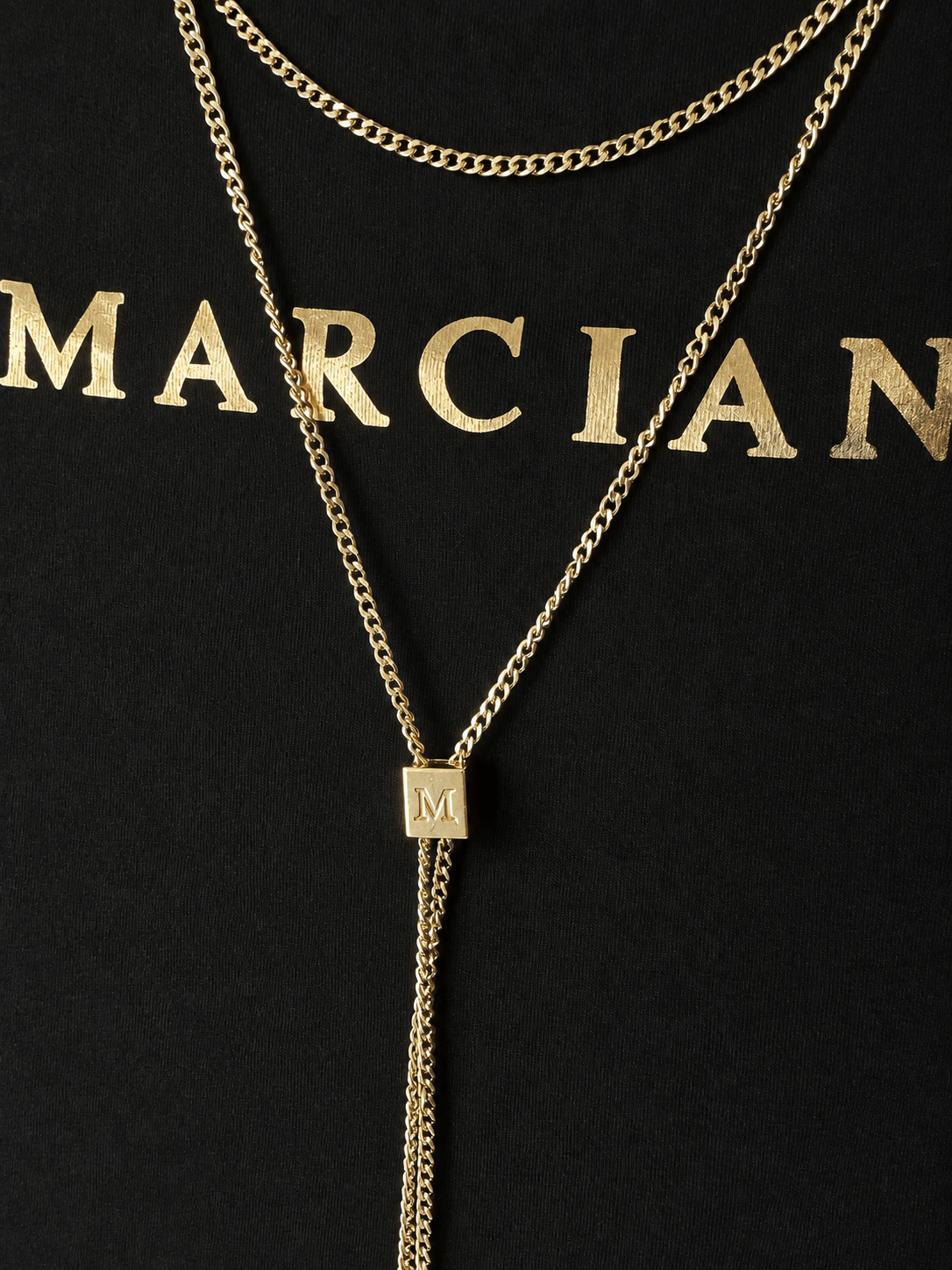 Detail van de goudkleurige ketting en het logo van een zwart Marciano by Guess T-shirt.